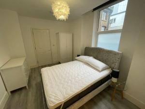 sypialnia z łóżkiem, oknem i żyrandolem w obiekcie Stunning 1 bed central flat w mieście Woking