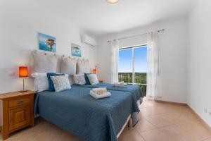 a bedroom with a bed with a blue bedspread and a window at Paz e Vista Mar with Pool & WiFi in Luz +30 photos