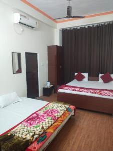 una camera d'albergo con due letti e una televisione di Goroomgo Varanasi Paradise Varanasi a Varanasi