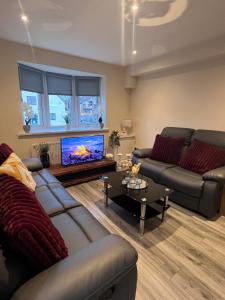 a living room with two couches and a flat screen tv at Pinfold Court Apartments in Knowsley