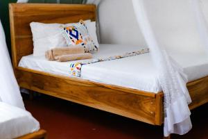 cama de madera con cortina y almohadas en Goodtimewithfar House, en Moshi