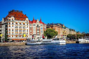 two boats in a river in front of buildings at Lägenhet med fantastiskt läge in Stockholm