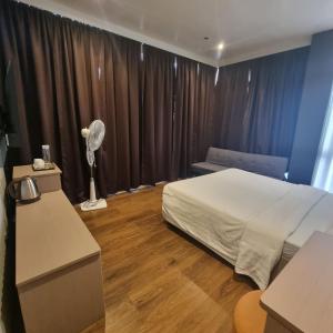 een slaapkamer met een bed en een bureau met een ventilator bij Eekos Hotels in Baguio