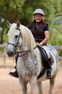 a woman is smiling while riding a white horse at Quinta do Archino 18 in Lisbon