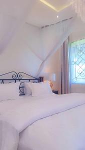 uma cama branca num quarto com uma janela em Amala villas em Arusha