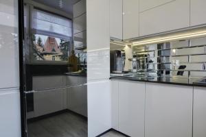 kuchnia z białymi szafkami i oknem w obiekcie Apartament Centrum w Polanicy Zdroju