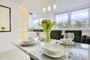 a dining room table with glasses and a vase of flowers at Apartament Centrum in Polanica-Zdrój