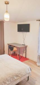 a bedroom with a desk and a tv on the wall at Green room in Asnières-sur-Seine