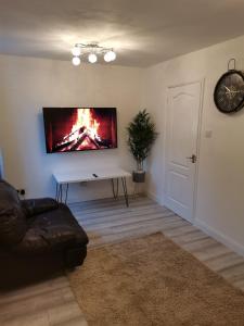 uma sala de estar com um sofá e uma televisão na parede em Newly Renovated Cosy 1 bed flat, 4 minutes walk to Town Centre, 3 minutes walk to the train station, Free parking, Modern, fresh and spacious living room, Netflix ready smart TV, Wifi em Wellingborough