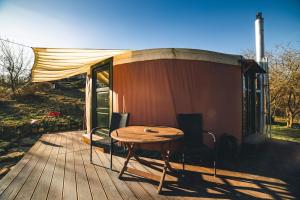 une terrasse en bois avec une table et une tente dans l'établissement GaiaMenedék Jurta, à Bakonynána