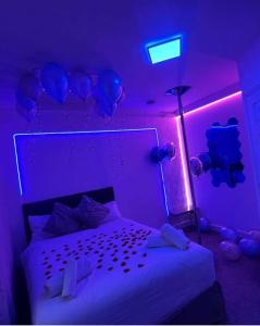 um quarto com uma cama com luzes roxas e balões em Luxury Urban Hideaway with private hot tub & Pole em Croydon