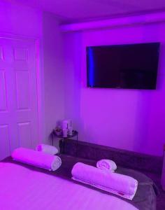um quarto roxo com uma cama com iluminação rosa em Luxury Urban Hideaway with private hot tub & Pole em Croydon