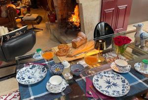 a table with plates and cups and a fireplace at Toute Une Histoire in Veneux-les-Sablons