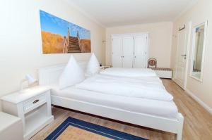 ein weißes Schlafzimmer mit einem großen weißen Bett. in der Unterkunft Wohnung Paul in Westerland