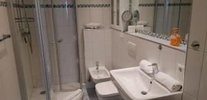 ein weißes Badezimmer mit Dusche und Waschbecken in der Unterkunft Wohnung Paul in Westerland + 9 Fotos