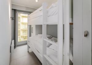 ein weißes Etagenbett in einem weißen Zimmer in der Unterkunft Wielingen 0302 in Oostduinkerke