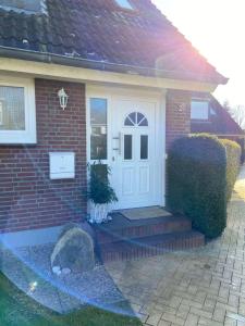 a brick house with a white door and a rock at Ferienwohnung Idylle auf Fehmarn I in Vitzdorf