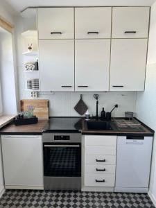 a kitchen with white cabinets and a sink and a stove at Ferienwohnung Idylle auf Fehmarn I in Vitzdorf