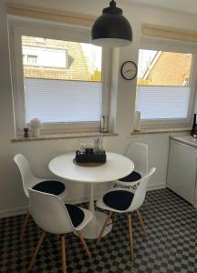 a white table and chairs in a kitchen with a clock at Ferienwohnung Idylle auf Fehmarn I in Vitzdorf +4 photos