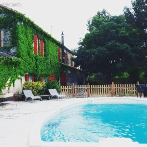 una piscina con due sedie e una casa di Chambres d'Hôtes, Domaine Les Peupliers a Lagnes