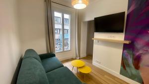 een woonkamer met een groene bank en een tv bij Bright apartment near Saint-Lazarre - 8P in Parijs