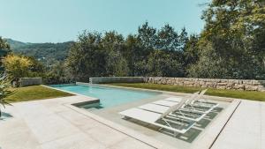 a swimming pool with two lounge chairs in a backyard at Casa da Cascata in Geres