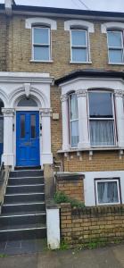 a brick house with a blue door and stairs at 1 Bedroom Flat 27 Mins to London Victoria in Sydenham