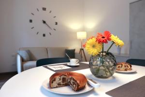 einen Tisch mit einem Teller Brot und eine Vase mit Blumen in der Unterkunft Residence Piazza Giotti 8 in Triest