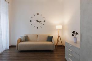 uma sala de estar com um sofá e um relógio na parede em Residence Piazza Giotti 8 em Trieste
