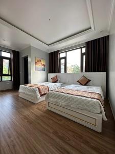 - 2 lits dans une grande chambre avec fenêtres dans l'établissement Việt Hoàng Hotel Hạ Long, à Hạ Long