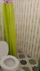 y baño con aseo y cortina de ducha. en HOTEL OASIS DOS MAX, en Ipiales