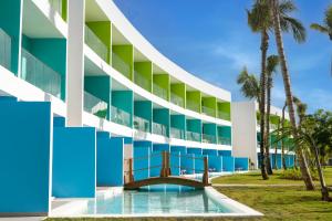 a building with a swimming pool and palm trees at Sunrise Miches Beach Resort, Punta Cana - All Inclusive - Adults Only in Punta Cana