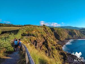 a group of people walking on a trail next to the ocean at Casa da Calheta in Maia