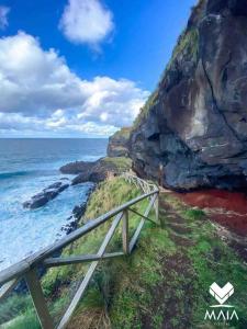 a wooden rail on the side of a cliff near the ocean at Casa da Calheta in Maia