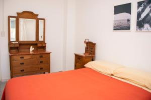 1 dormitorio con cama, tocador y espejo en Departamento Blanco en Tandil