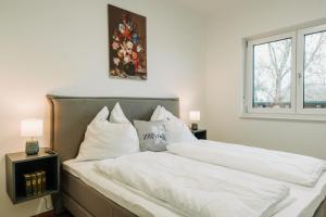 a bedroom with a large bed with white sheets and pillows at Weingut Zweytick Lodge Vinoment in Ehrenhausen