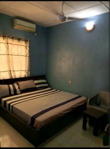 1 dormitorio con 1 cama y 1 silla en Hibis k hotel (green gate), en Lagos