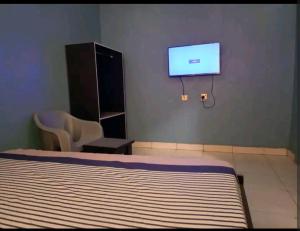a bedroom with a bed and a flat screen tv at Hibis k hotel (green gate) in Lagos