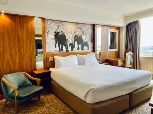 哈拉雷的住宿－莫諾莫塔帕酒店，酒店客房带一张大床和一把椅子