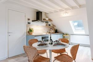 a kitchen with a white table and chairs at Bright apartment close to the sea in Ostend