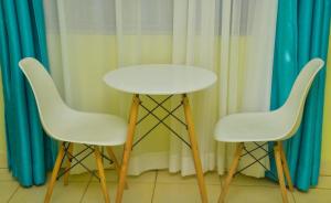 two white chairs and a white table in front of curtains at The O,S Homestay in Chuka