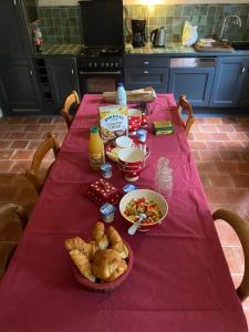 einen Tisch mit einem roten Tischtuch mit Futter drauf in der Unterkunft Gîte de la vallée in Volnay