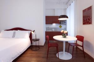 Residence Piazza Giotti 8 في ترييستي: غرفة صغيرة بسرير وطاولة وكراسي
