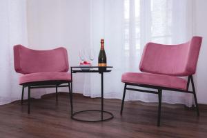 2 sedie rosa e una bottiglia di vino su un tavolo di Residence Piazza Giotti 8 a Trieste