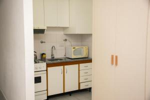 cocina con armarios blancos y microondas en Departamento Blanco en Tandil