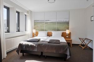 a bedroom with a large bed with two pillows at Hunzego Hotel in Uithuizermeeden