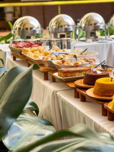 una línea de buffet con platos de comida en las mesas en Castro's Park Hotel, en Goiânia