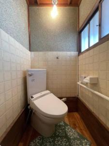 uma casa de banho com um WC branco e uma janela em Nogataの商店街の一角にあるちいさな隠れ家　忘覚庵 em Nōgata
