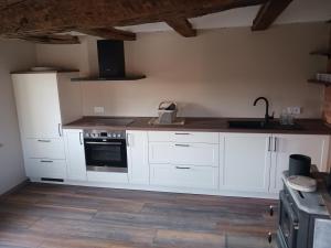 a kitchen with white cabinets and a sink and a stove at Alte Schule in Grebenhain