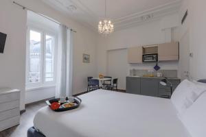 a bedroom with a large white bed and a kitchen at Residence Piazza Giotti 8 in Trieste